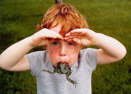 Kleiner rothaariger Junge mit Sommersprossen hat einen Frosch im Mund